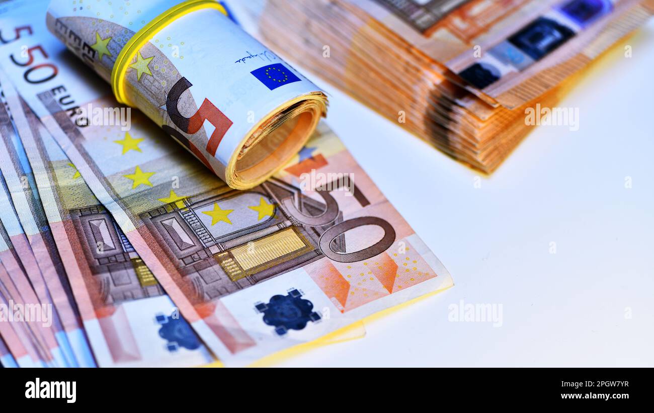 Concetto di molti euro: Un mucchio di banconote arrotolate da 50 euro giacenti su uno sfondo bianco, pila di banconote da 50 euro background commerciale Foto Stock