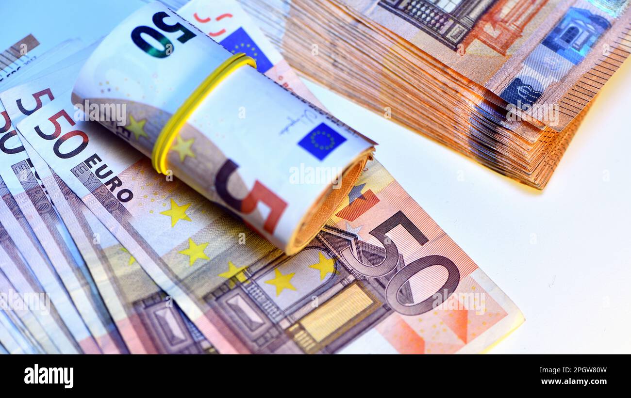 Concetto di molti euro: Un mucchio di banconote arrotolate da 50 euro giacenti su uno sfondo bianco, pila di banconote da 50 euro background commerciale Foto Stock