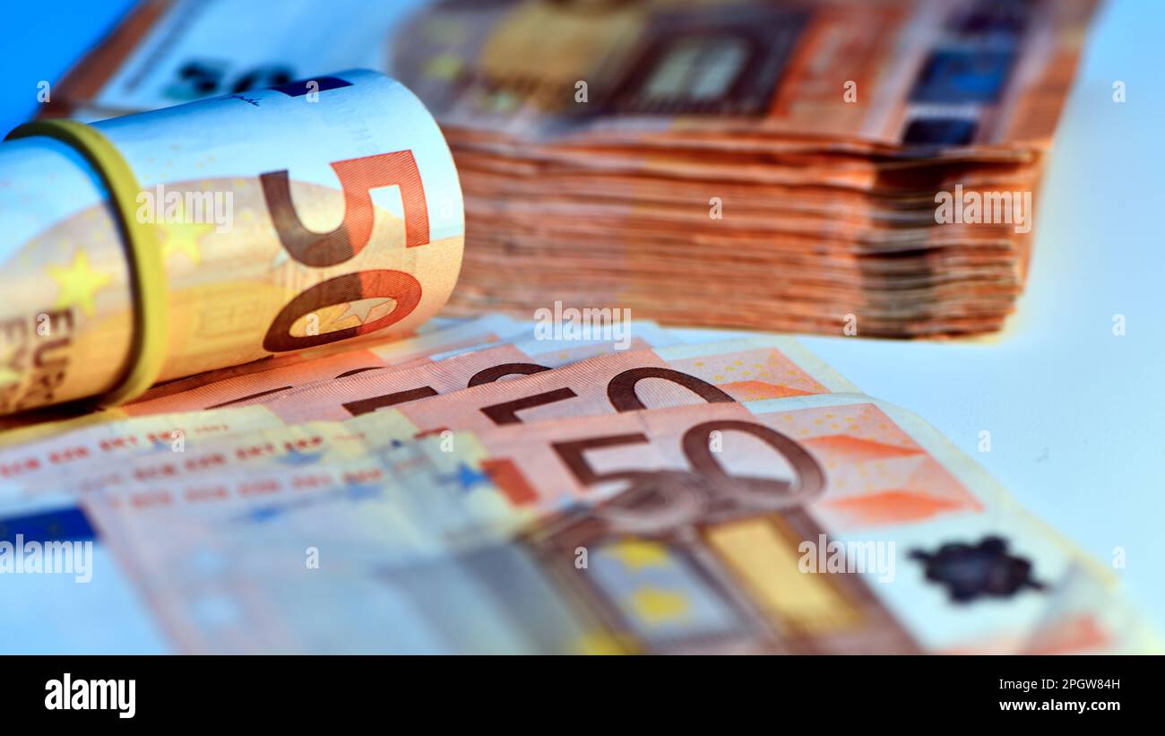 Concetto di molti euro: Un mucchio di banconote arrotolate da 50 euro giacenti su uno sfondo bianco, pila di banconote da 50 euro background commerciale Foto Stock