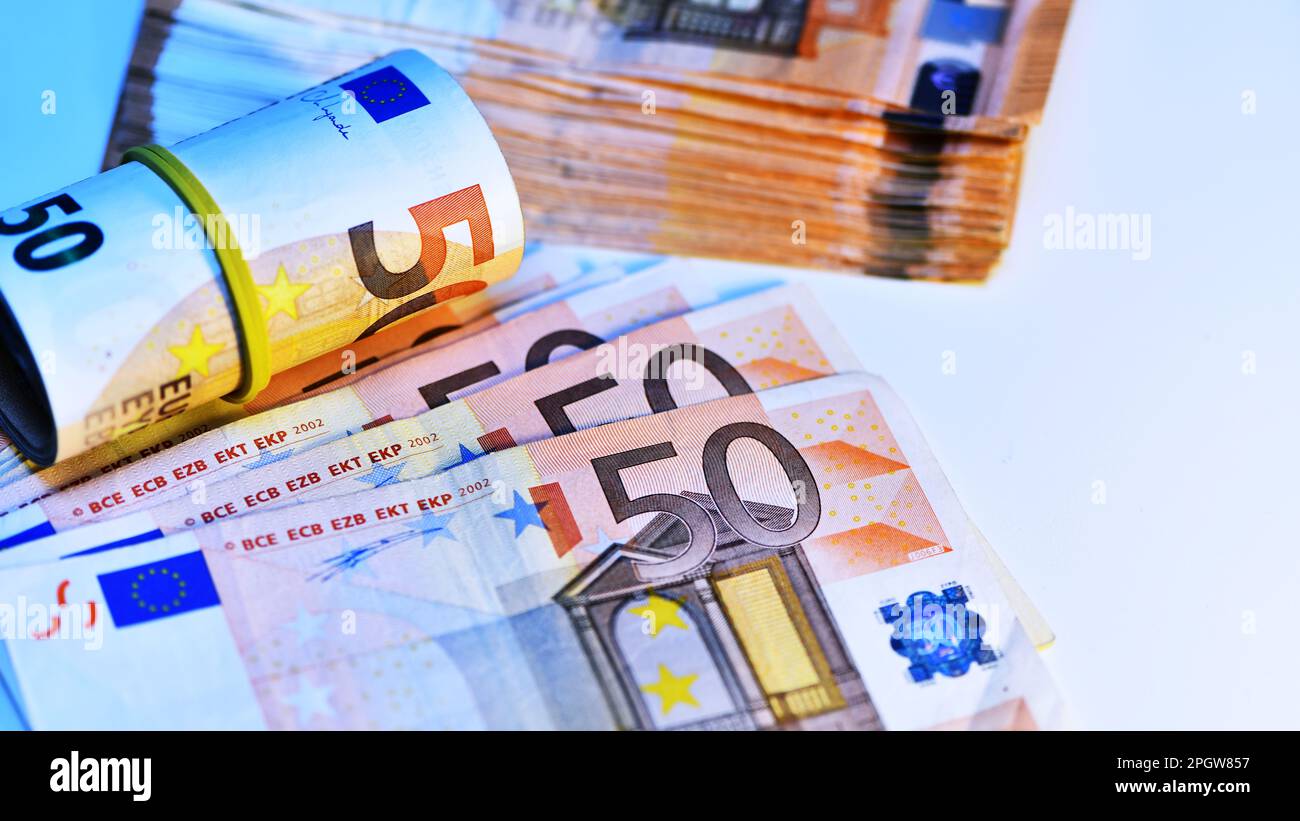 Concetto di molti euro: Un mucchio di banconote arrotolate da 50 euro giacenti su uno sfondo bianco, pila di banconote da 50 euro background commerciale Foto Stock
