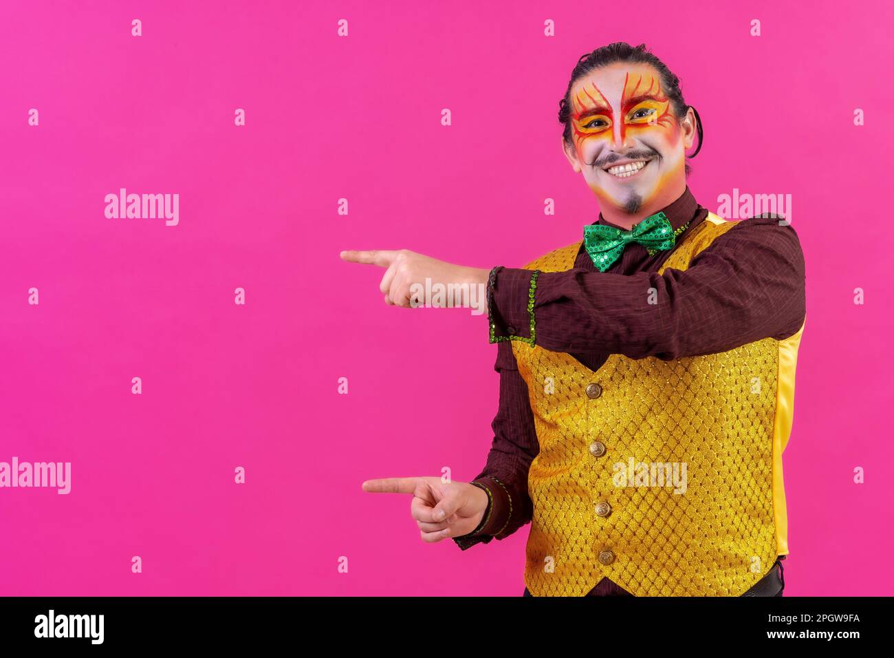 Un allegro performer da circo che punta su uno sfondo rosa vuoto per il copyspace Foto Stock