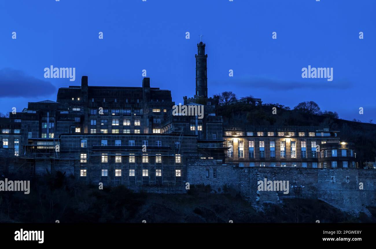 Il quartier generale del Governo Scozzese St Andrew's House, edificio illuminato di notte con il Nelson Monument a Calton Hill, Edimburgo, Scozia, Regno Unito Foto Stock