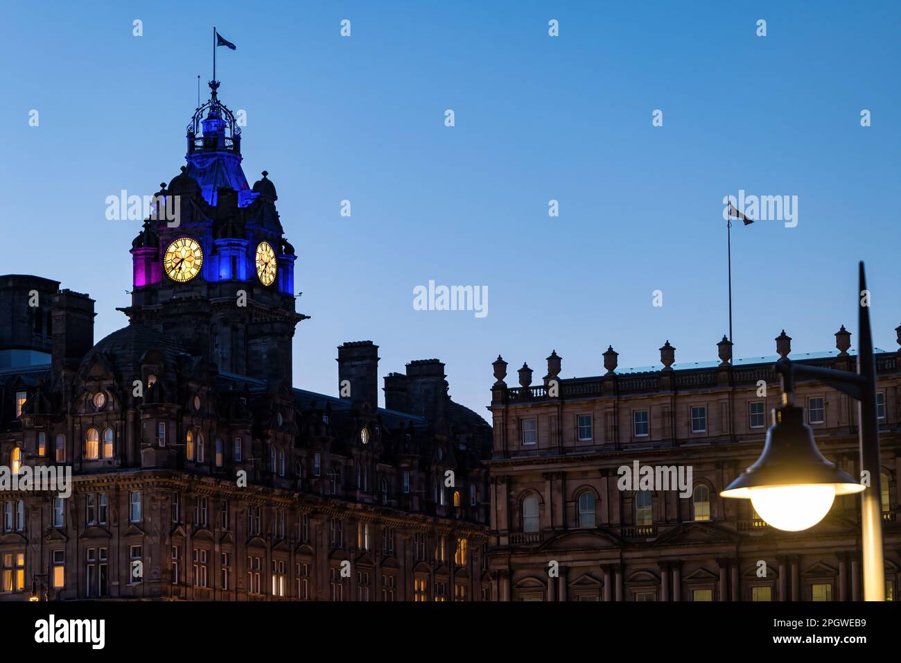 La torre dell'orologio del Balmoral Hotel, illuminata al crepuscolo o al crepuscolo con un cielo limpido, Edimburgo, Scozia, Regno Unito Foto Stock