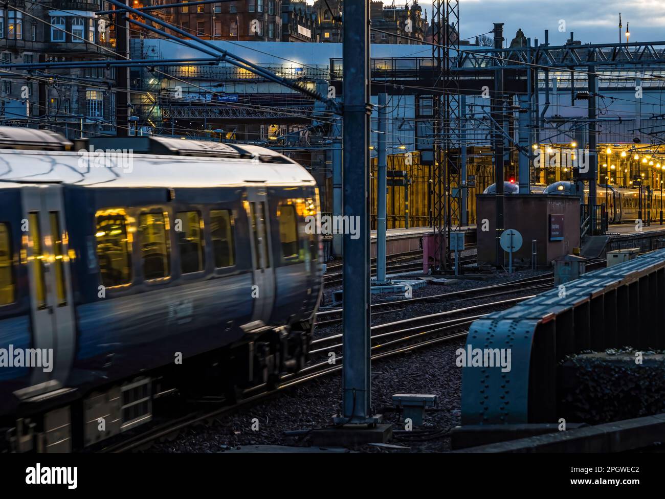 Treno che si avvicina alla stazione ferroviaria di Waverley illuminata di notte, Edimburgo, Scozia, Regno Unito Foto Stock