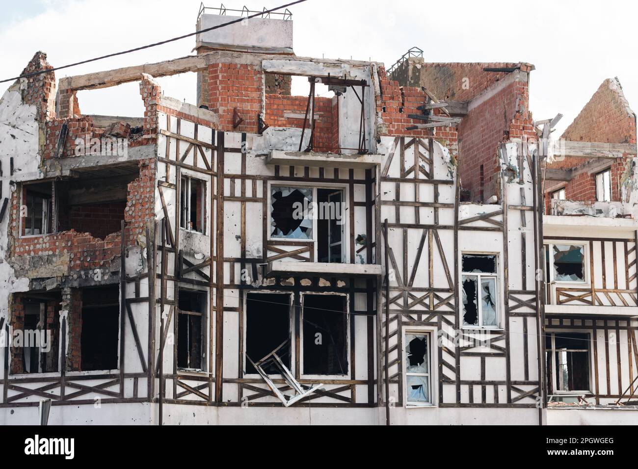 Distrutto edificio dopo l'invasione russa, Ucraina. Facciata in rovina della casa con design fachwerk. Guerra in Ucraina. Finestre e muri in mattoni rotti. Foto Stock