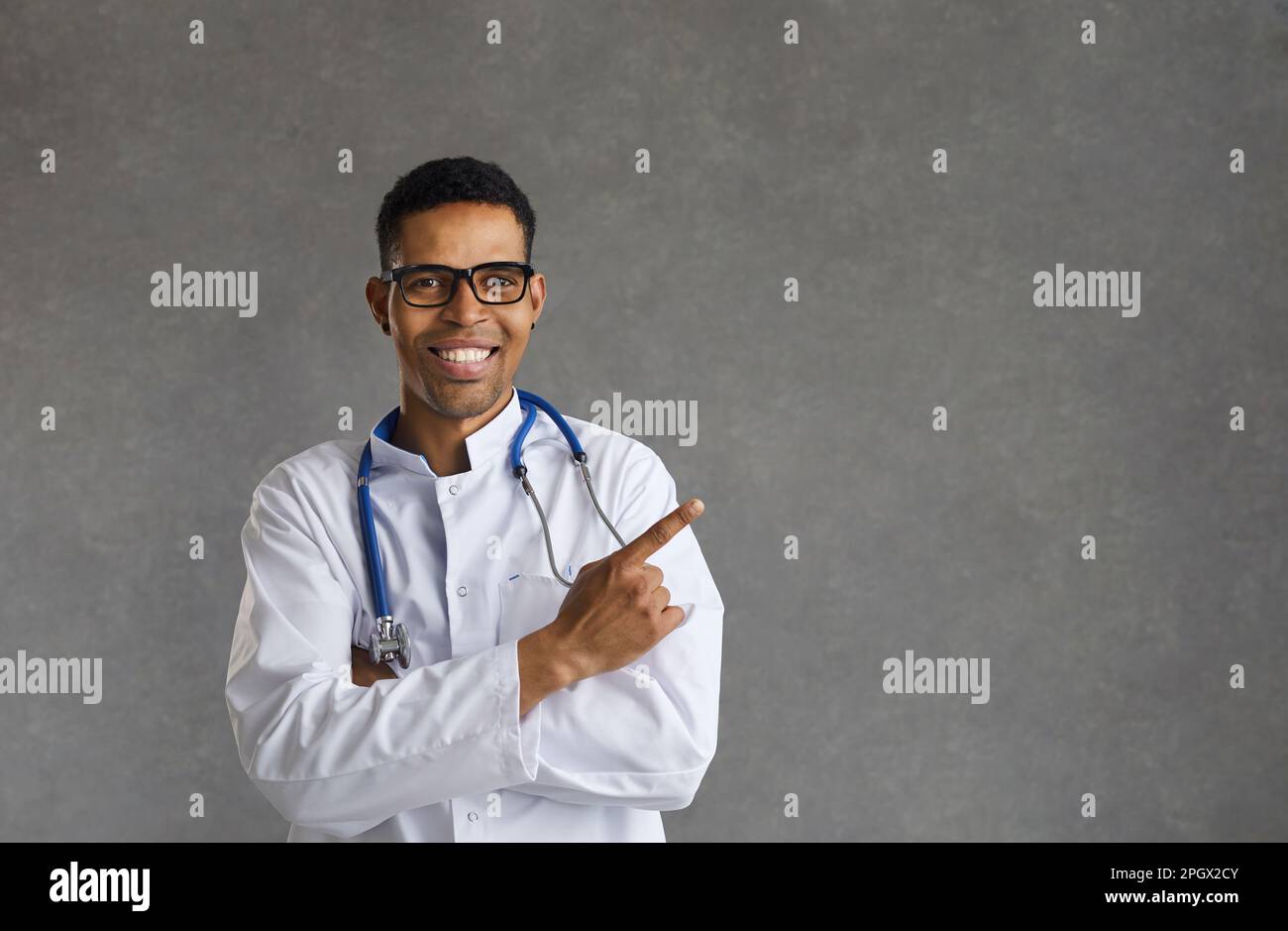Amichevole sorridente medico afro-americano maschio che indica con il dito da parte Foto Stock