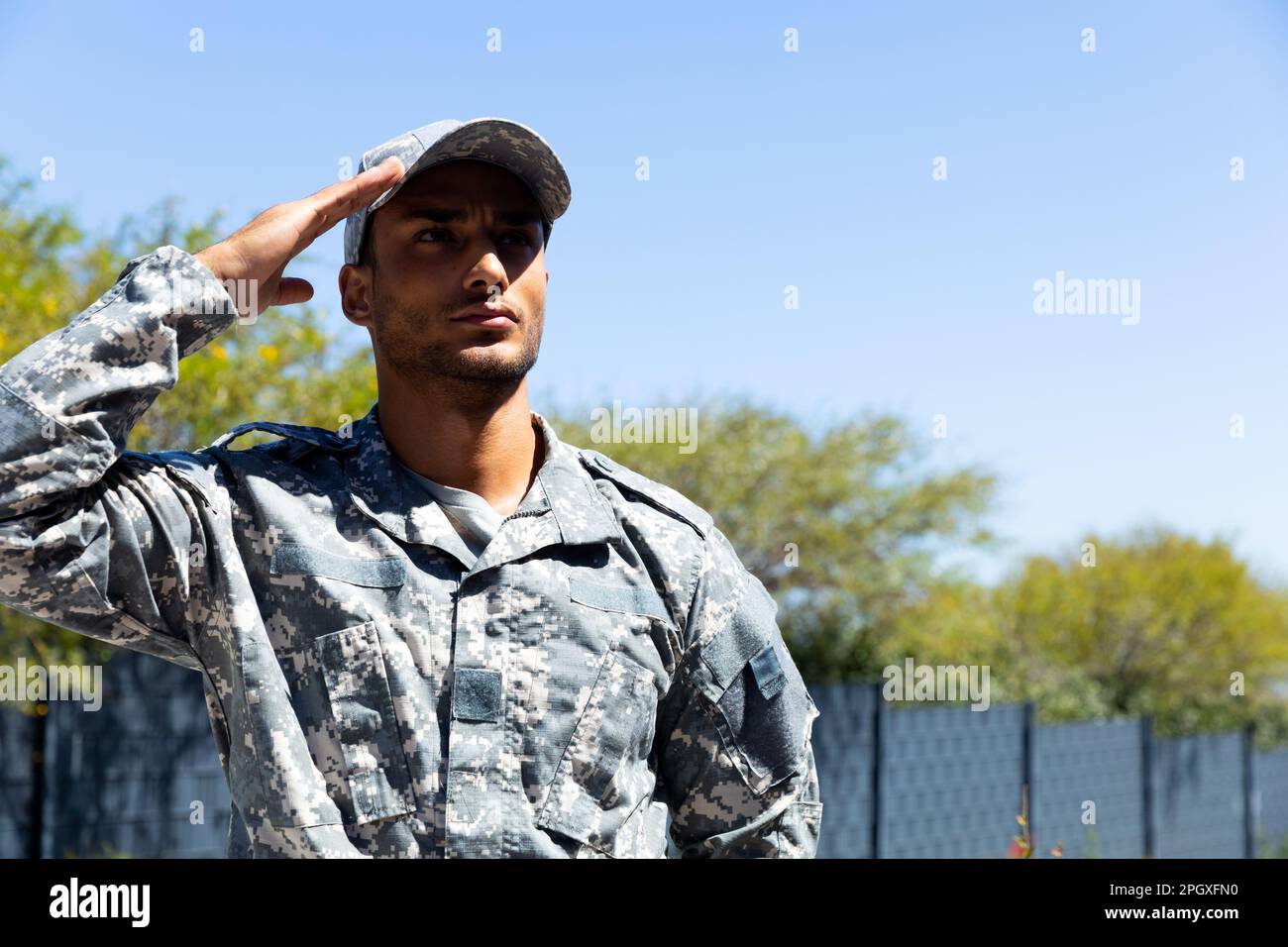 Soldato biraciale maschile in uniforme militare, saluta all'aperto, con spazio copia Foto Stock