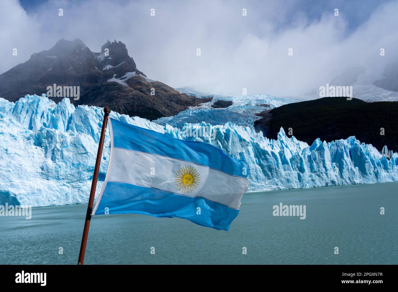 Una bandiera argentina su una barca con il ghiacciaio Upsala sullo sfondo. Foto Stock