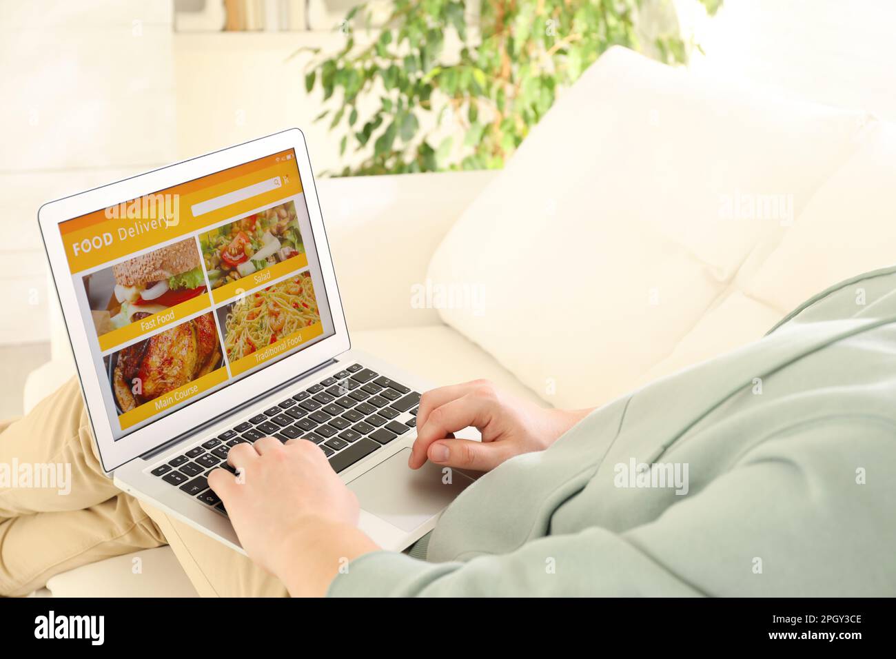 Uomo che usa il laptop per ordinare cibo online a casa, primo piano. Servizio di consegna Foto Stock