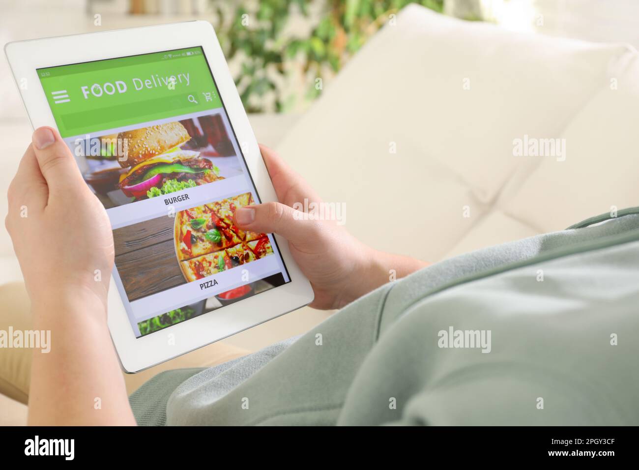 Uomo che usa il tablet per ordinare cibo online a casa, primo piano. Servizio di consegna Foto Stock