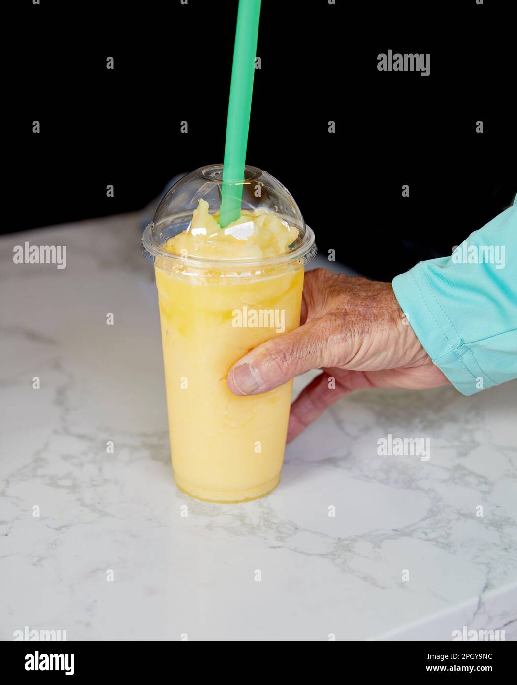 Mano dell'uomo che tiene un frullato tropicale in una tazza Foto Stock