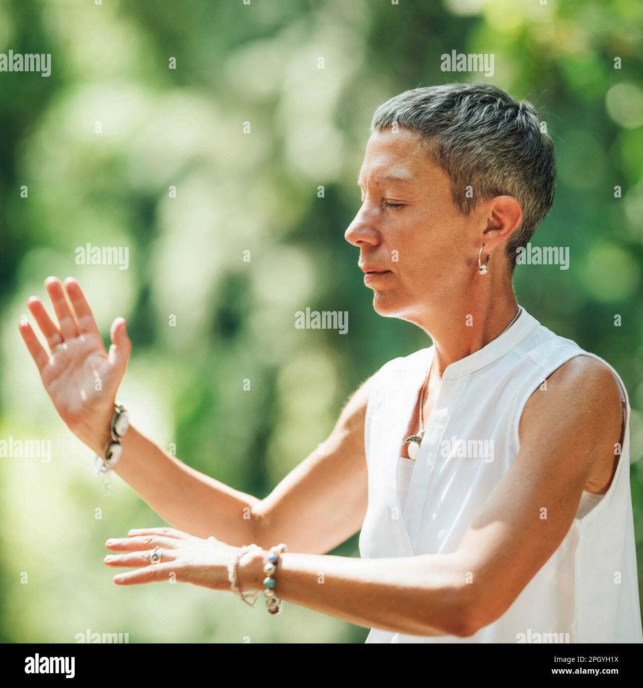 Donna che pratica il qigong in una foresta Foto Stock