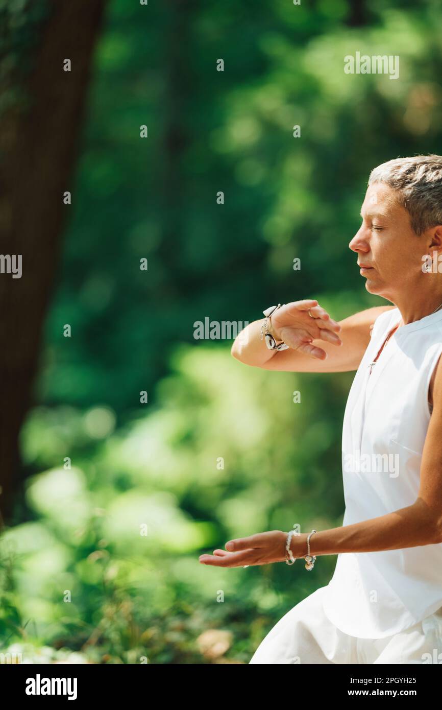 Donna che pratica il qigong in una foresta Foto Stock