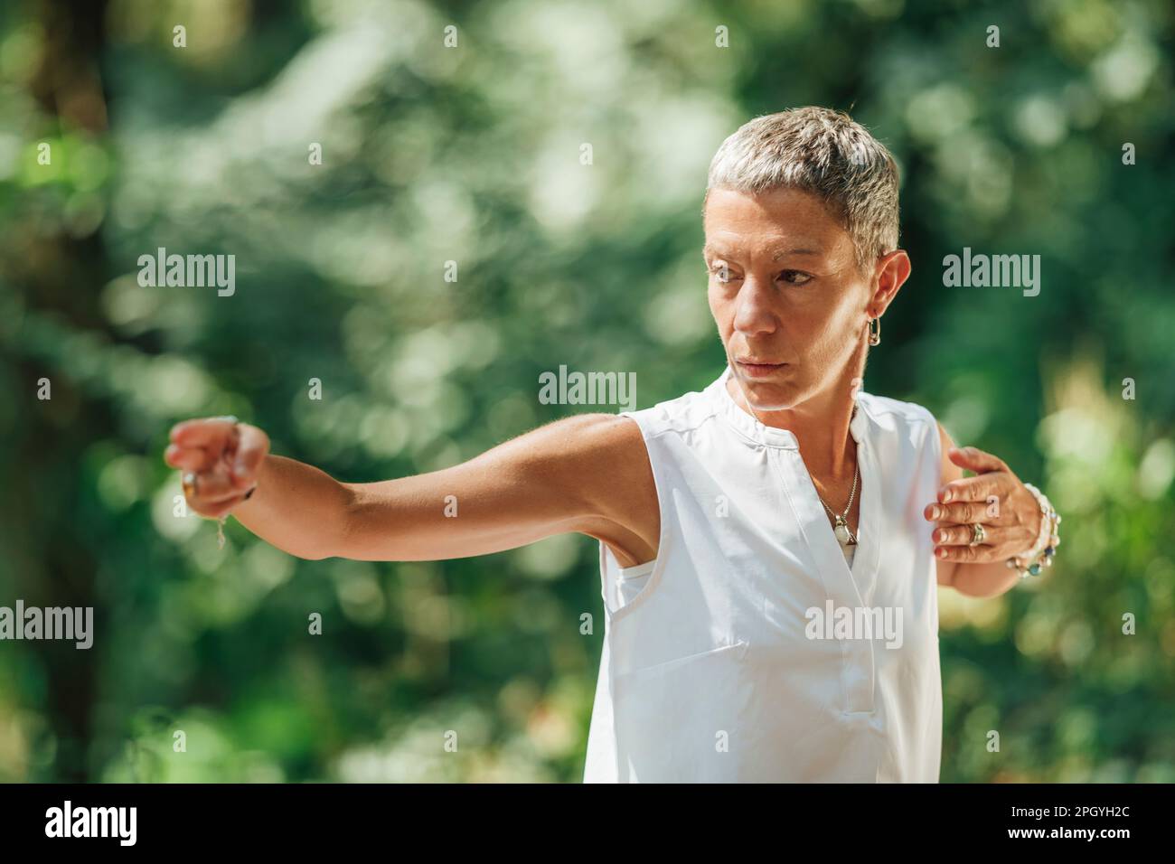 Donna che pratica il qigong in una foresta Foto Stock