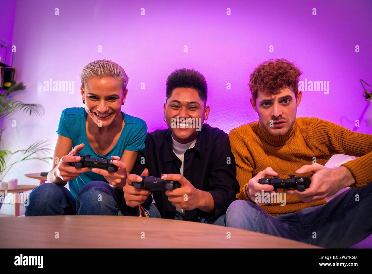 Gruppo di giovani amici che giocano insieme sul divano di casa, ritratto guardando la fotocamera Foto Stock