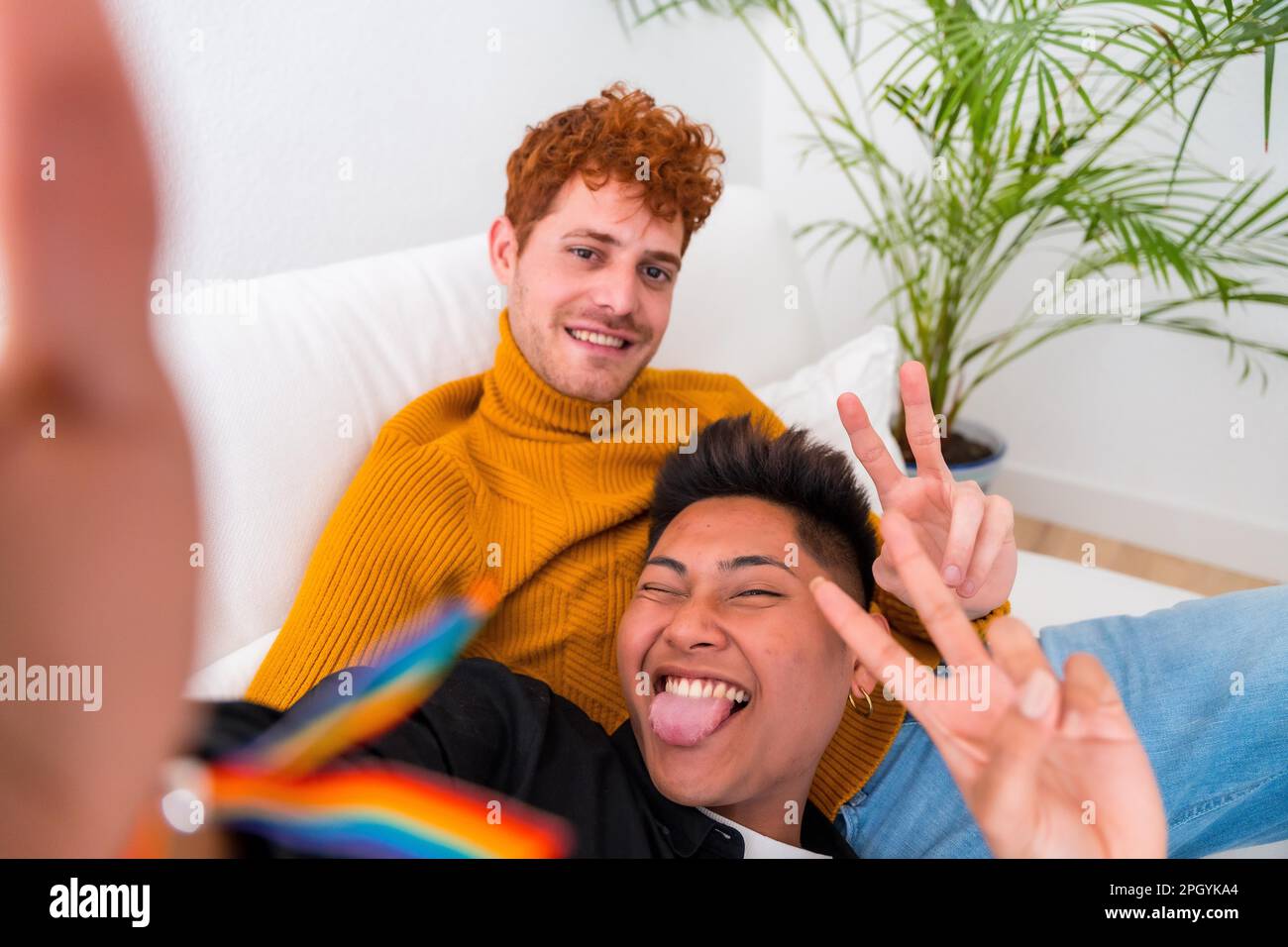 Bella coppia gay essere romantico al coperto a casa sul divano, coppia gay prendere selfie e fare segno di vittoria, lgbt concetto Foto Stock