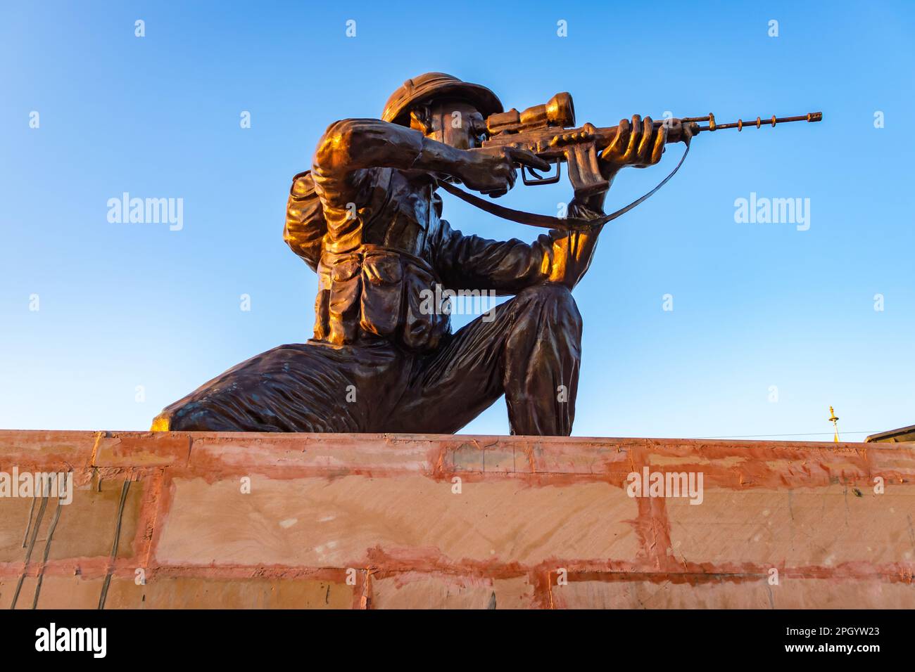 statua soldato isolata con pistola da diverse angolazioni con cielo luminoso di sera Foto Stock