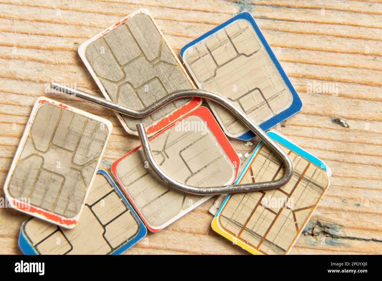 le schede sim e un perno per l'apertura dell'alloggiamento di una scheda sim si trovano su un tavolo di legno Foto Stock