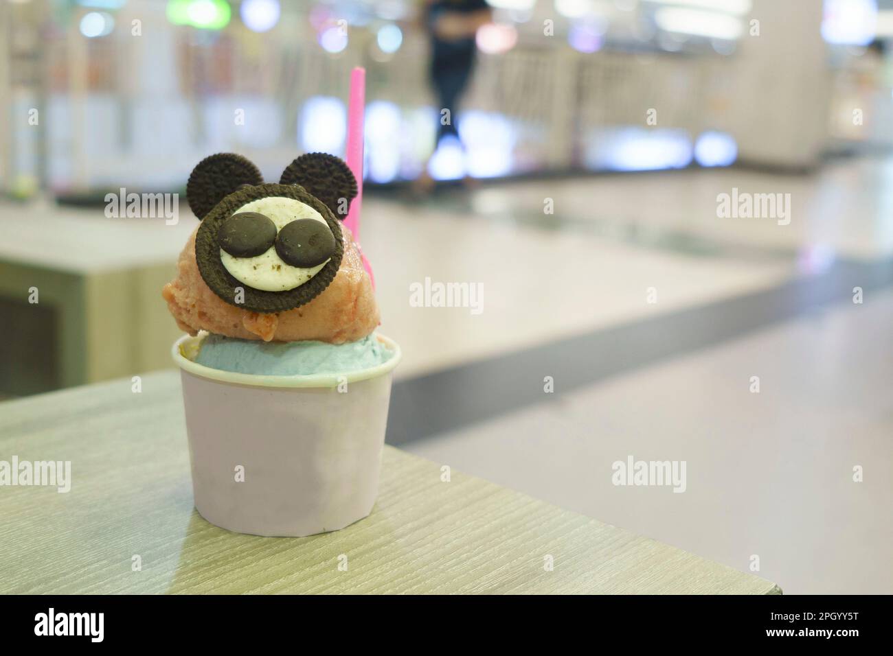 Una tazza di gelato con la guarnizione di biscotto simile al topo servita sul tavolo di legno con fondo sfocato. Foto Stock