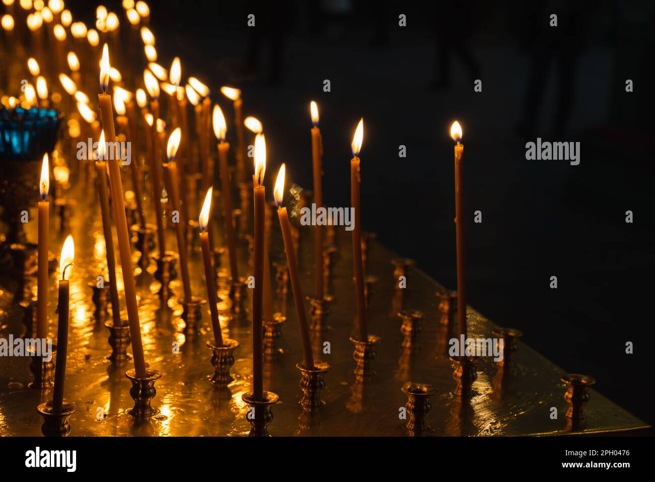 Le candele ortodosse di cera d'api bruciano in un interno scuro della Chiesa Foto Stock