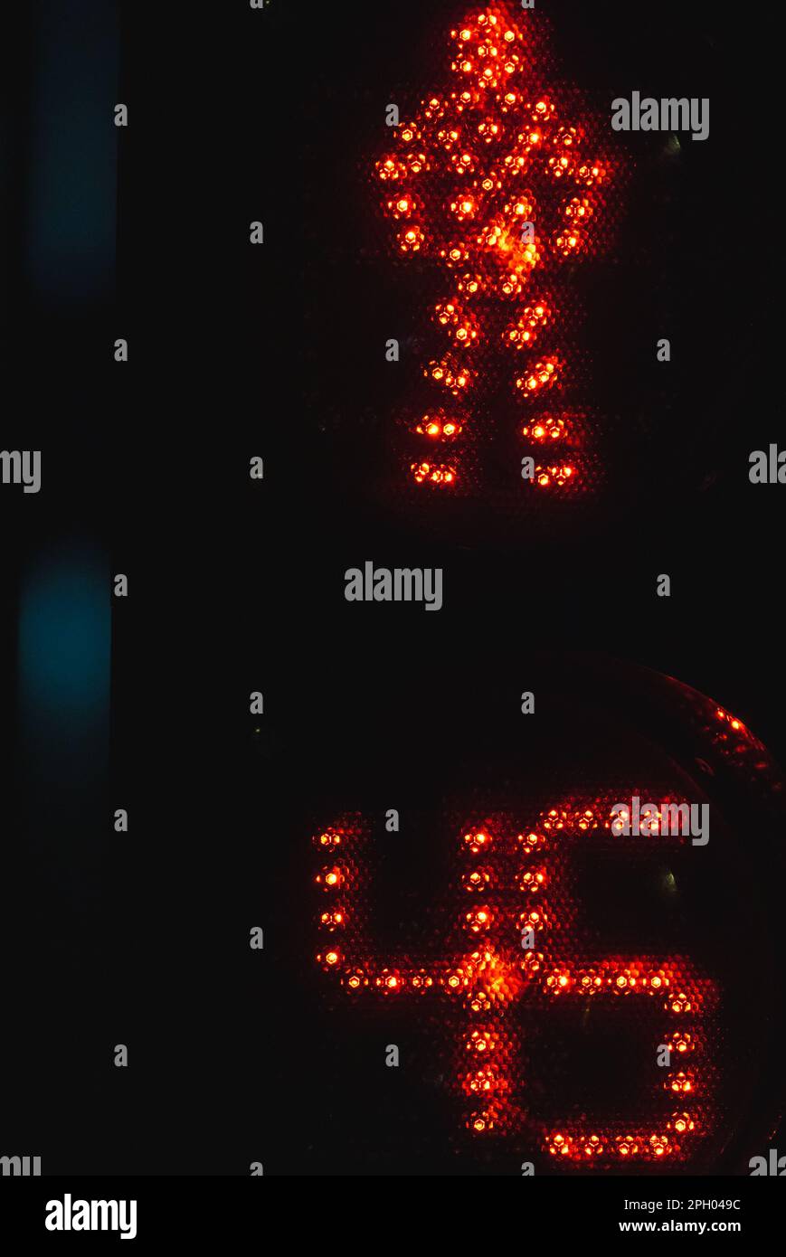 Il semaforo pedonale con timer mostra il segnale di stop rosso con un cartello a LED MAN su sfondo nero notturno, foto ravvicinata verticale Foto Stock