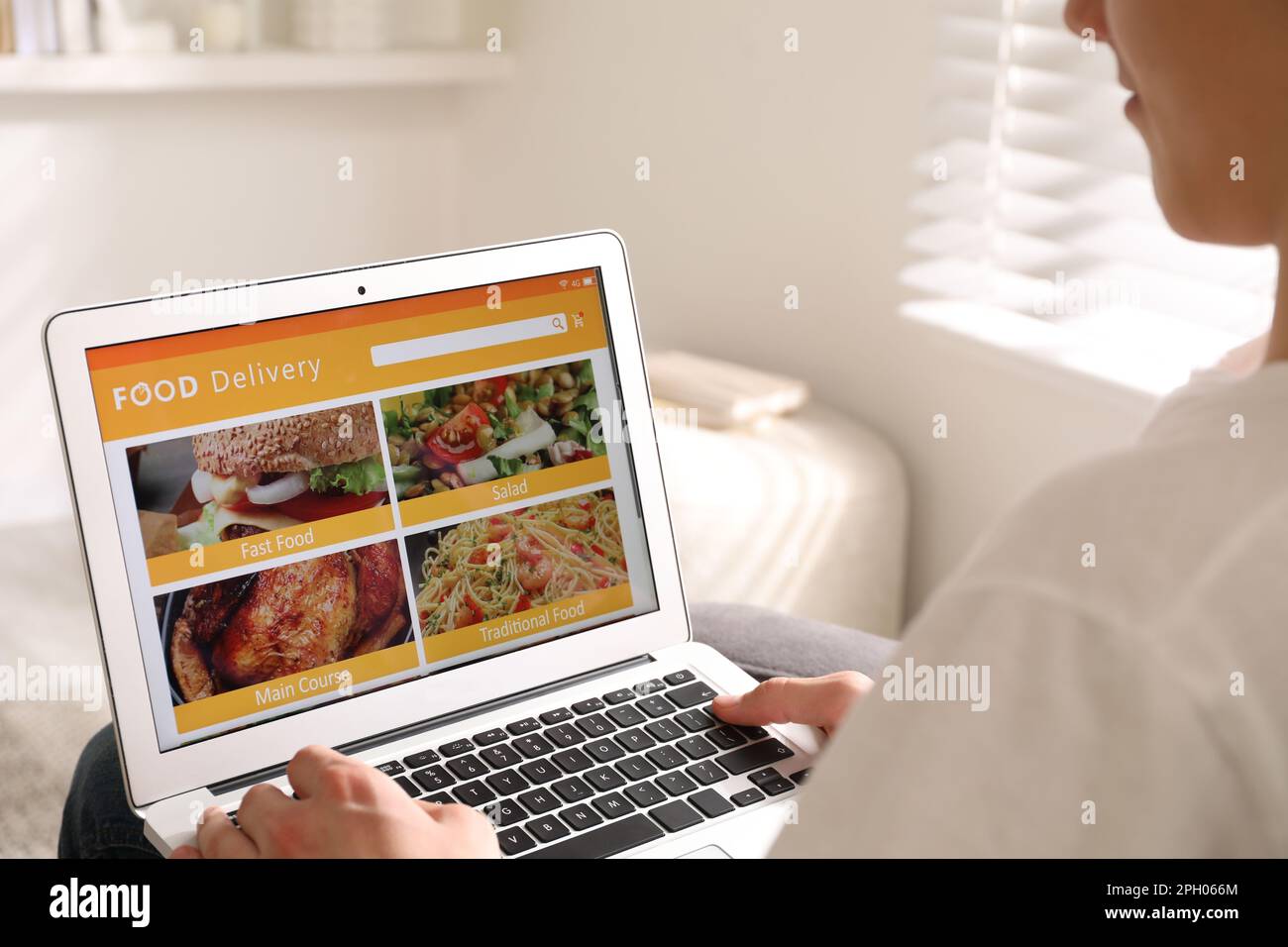 Uomo che usa il laptop per ordinare cibo online a casa, primo piano. Servizio di consegna Foto Stock