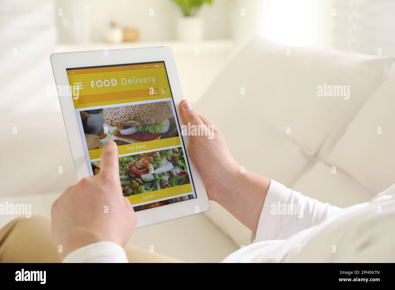 Uomo che usa il tablet per ordinare cibo online a casa, primo piano. Servizio di consegna Foto Stock