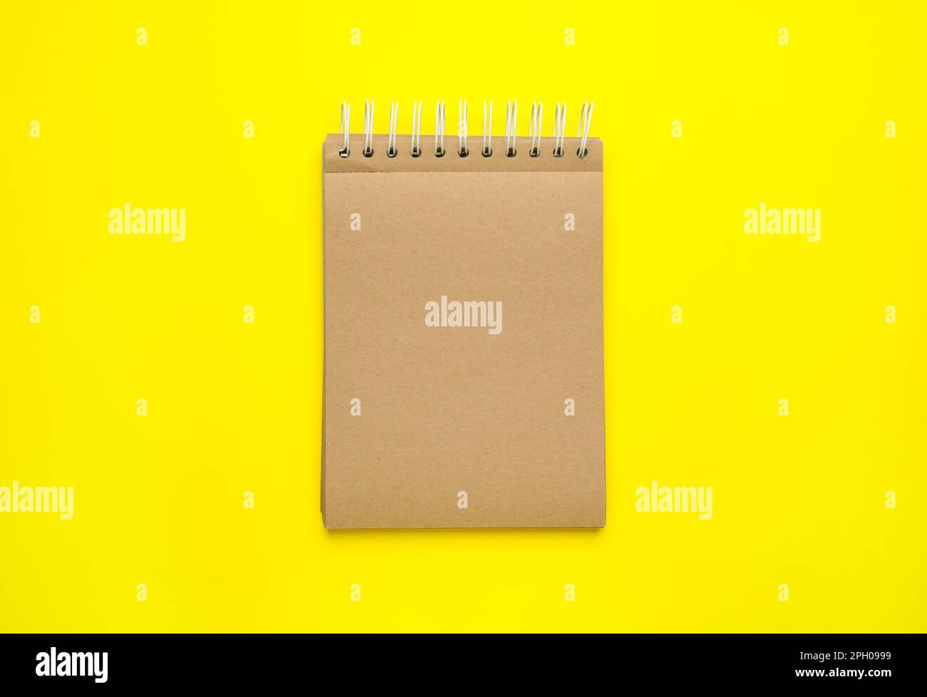 Notebook con pagine di carta marrone su sfondo giallo, vista dall'alto Foto Stock