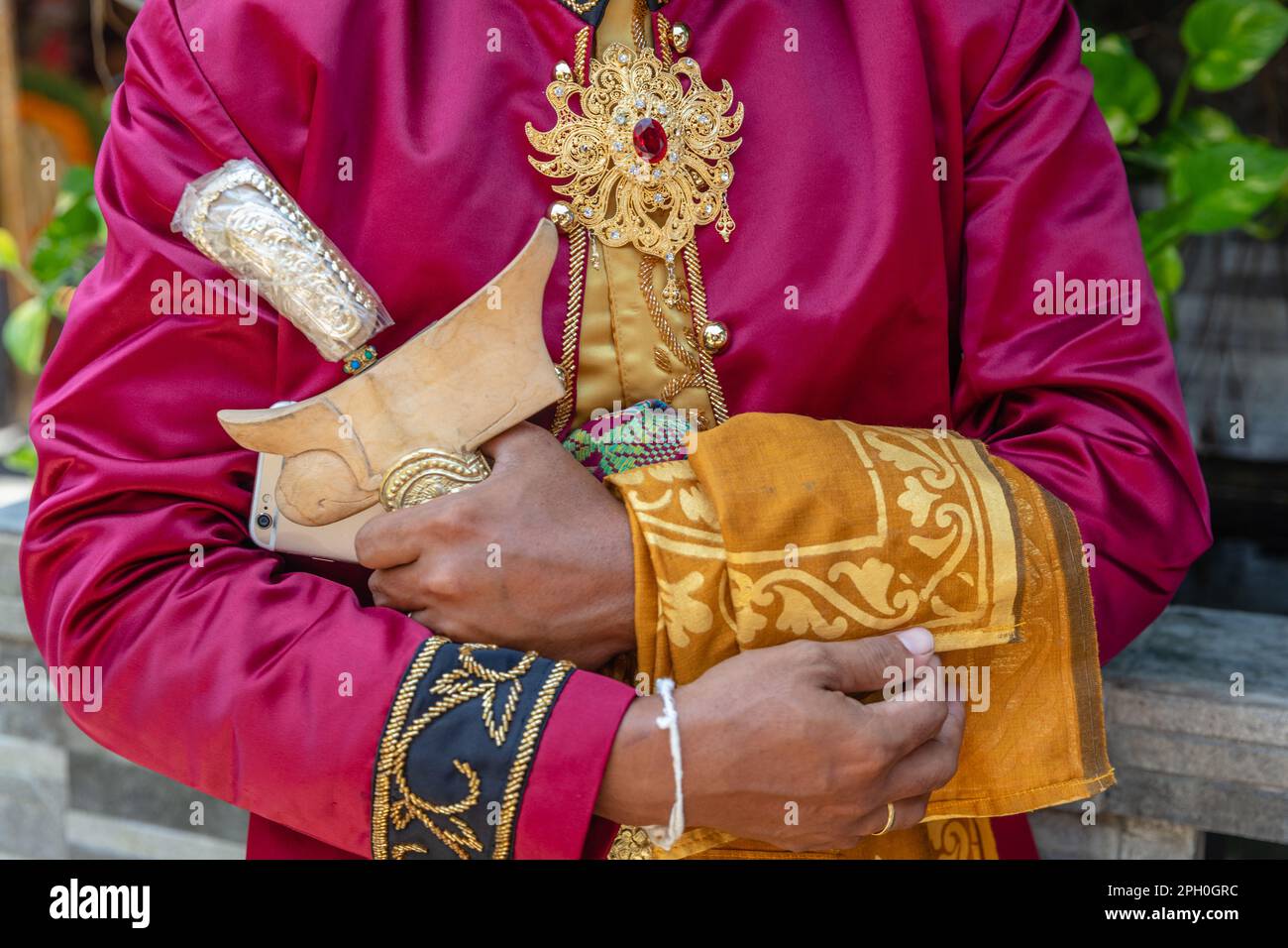 Tradizionale abito da sposa balinese maschio, gioielli d'oro e un coltello cerimoniale kris. Bali, Indonesia. Foto Stock