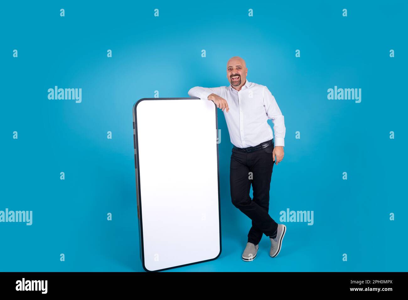 Allegro uomo di mezza età che si appoggia grande cellulare mock up. Smartphone con schermo bianco vuoto per il posizionamento del prodotto. Concetto di pubblicità del Web site dell'applicazione Foto Stock