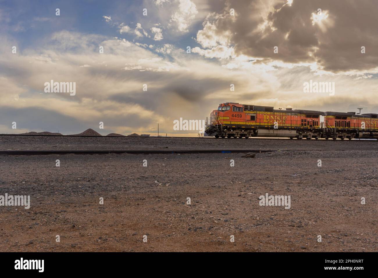 Un treno BNSF Railway arancione brillante viaggia attraverso il deserto di Yeso, New Mexico. Foto Stock