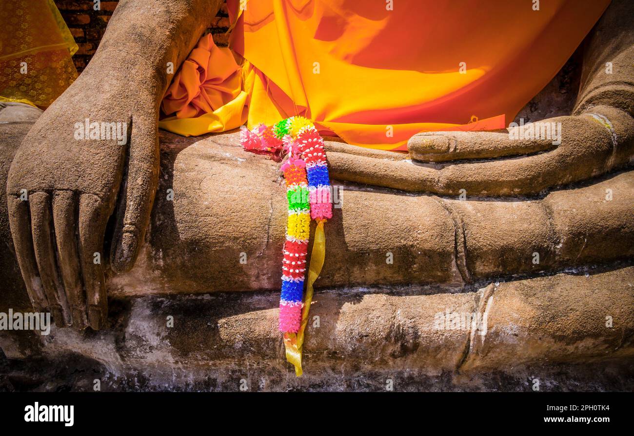 Particolare della Statua del Buddha nel Tempio di Wat Mahathat con la corona colorata che gli è posta sulle mani, il Parco storico di Sukhothai, Thailandia Foto Stock