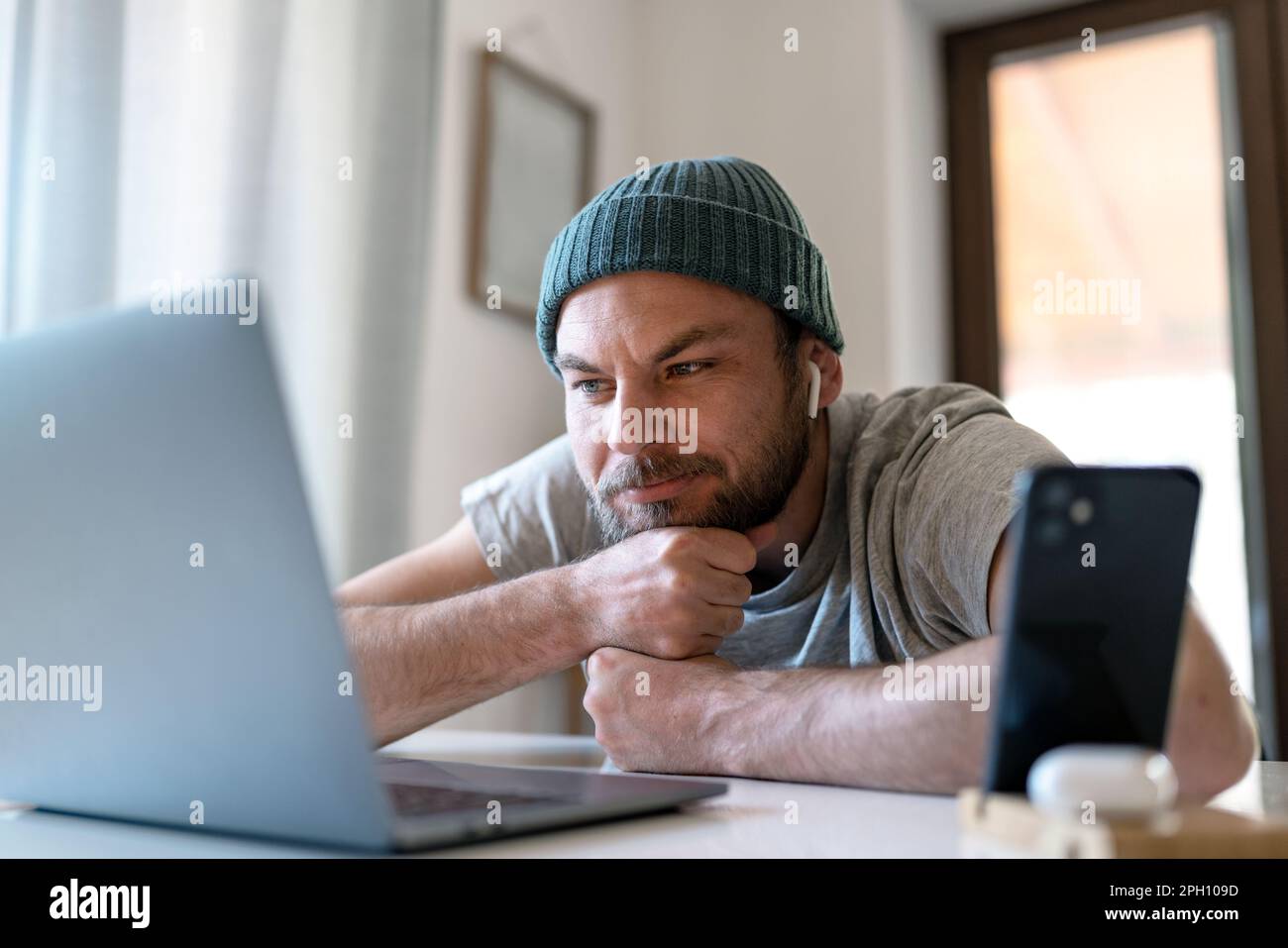 Giovane uomo adulto che guarda vlog su internet e sorridente. Foto Stock