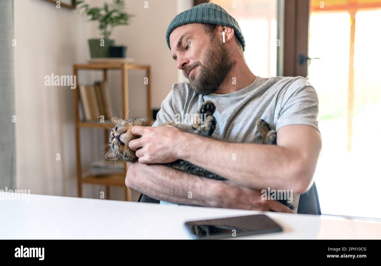 L'uomo e il suo gatto si rilassano a casa. Foto Stock