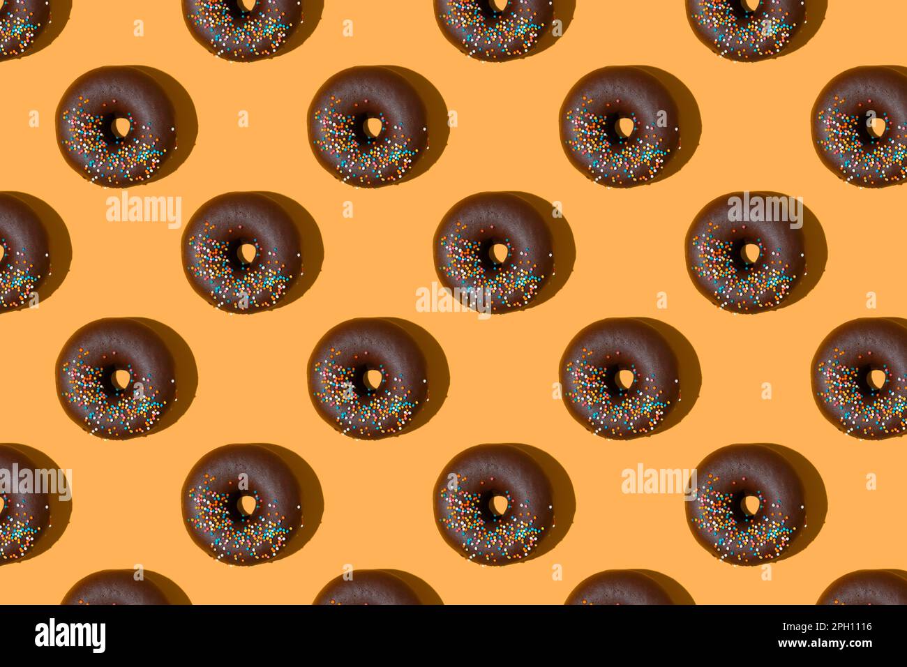 Ciambelle al cioccolato modello isolato su sfondo arancione. Panetteria, ciambella, delizia, cibo dolce. Vista dall'alto, disposizione piatta, sfondo, sfondo Foto Stock