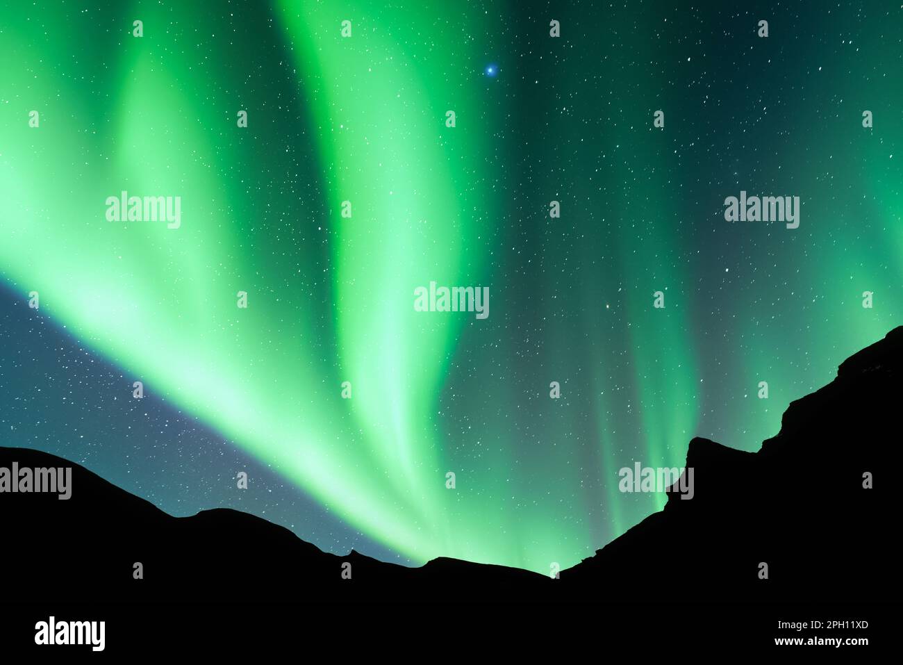 Cielo notturno con Aurora borealis aurora aurora boreale in montagna d'inverno. Cielo con luci polari e stelle con colline scure. Fotografia di paesaggi Foto Stock