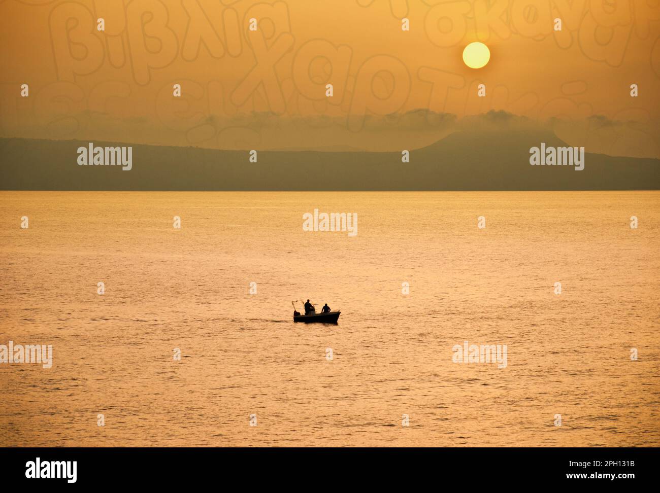 Rethymnon tramonto con i pescatori in piccola barca, il cielo ha alcune lettere greche / scrittura incorporata Foto Stock