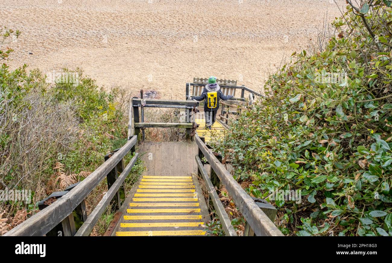 Donna non identificabile che scende i gradini per la spiaggia di pietra Foto Stock