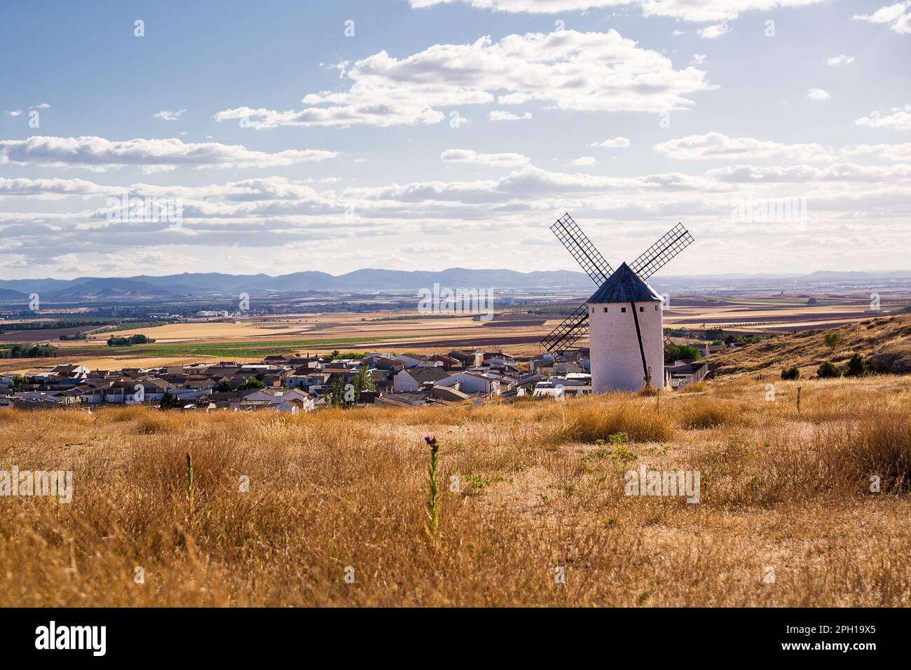 Campo secco con antico mulino a vento e sotto il villaggio di campo de Criptana, Spagna, definito in Cervantes 'Don Chisciotte 'i Giganti' Foto Stock