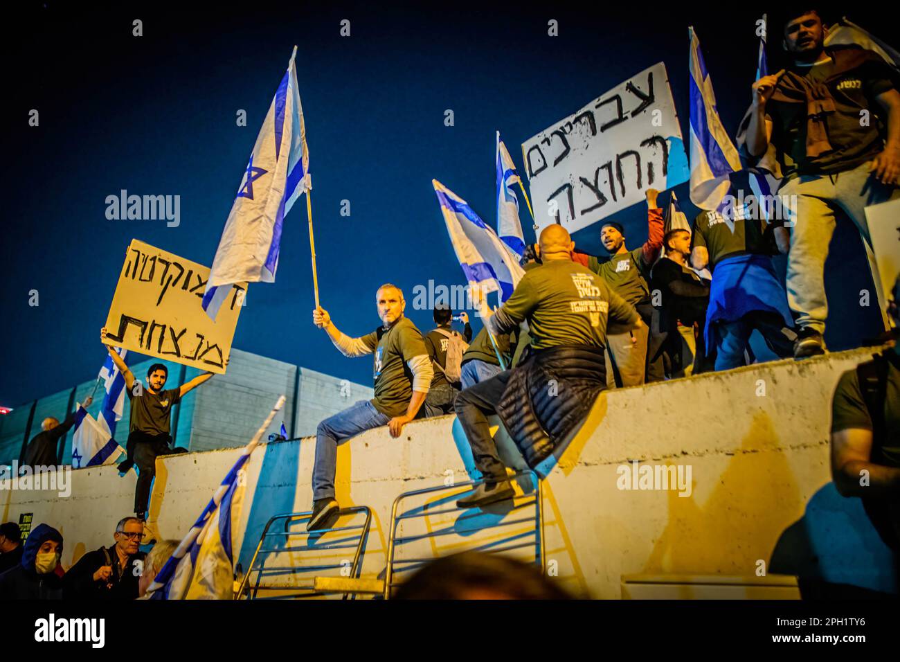 I manifestanti israeliani detengono bandiere e cartelli durante una protesta contro la riforma giudiziaria. Il primo ministro israeliano Benjamin Netanyahu Giovedi ha promesso di porre fine alla frattura in una nazione profondamente divisa sulla sua proposta di revisione della magistratura del paese, Netanyahu ha presentato il suo appello in un discorso televisivo nazionale dopo un altro giorno di proteste di massa in tutto il paese contro il piano. I suoi vaghi impegni sono stati rapidamente respinti dal movimento di protesta, che ha detto che avrebbe continuato ad opporsi al tentativo di Netanyahu di diventare un dittatore. (Foto di Eyal Warshavsky/SOPA Images/Sipa USA) Foto Stock