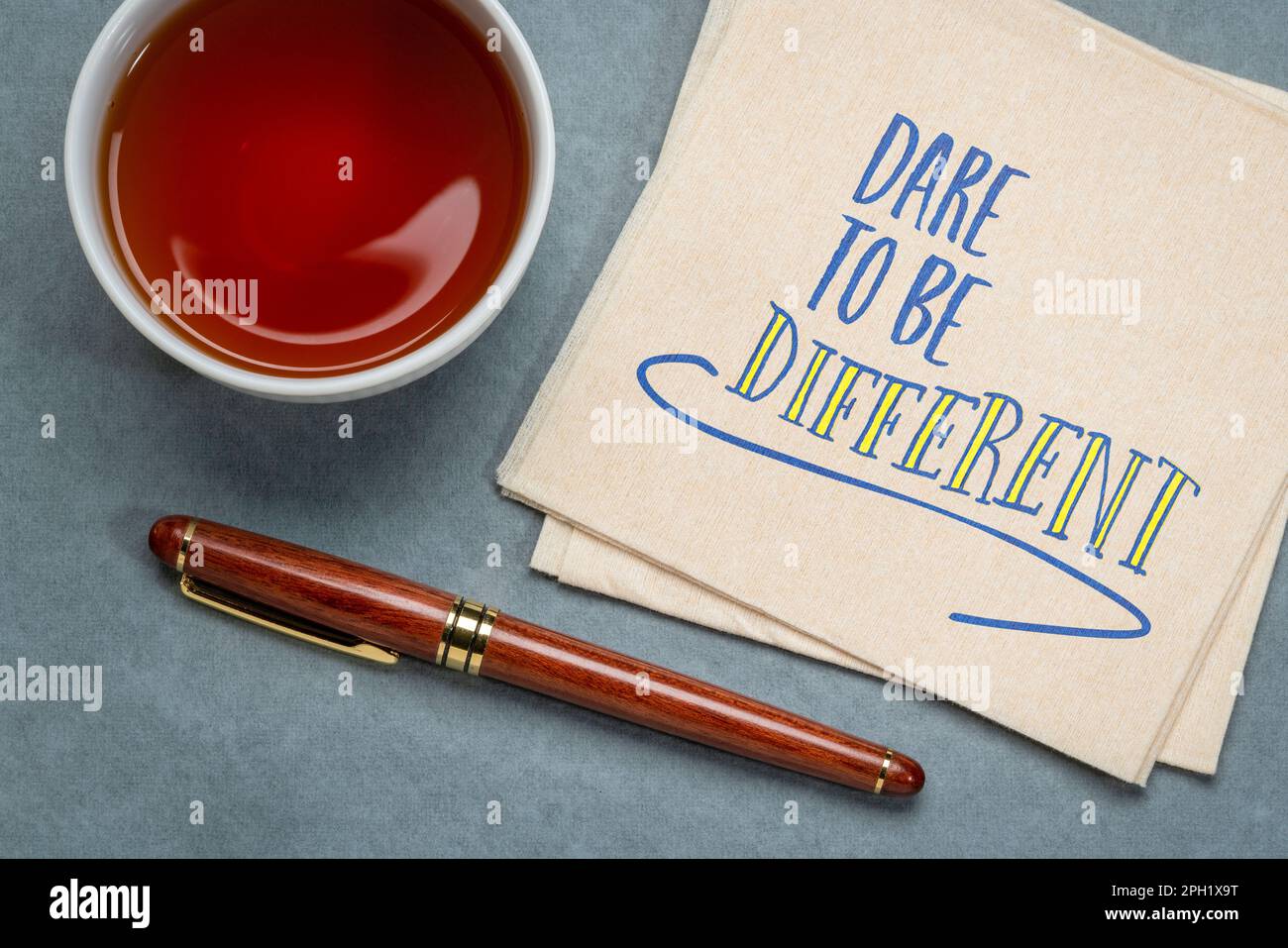 osate essere differenti - nota di ispirazione, scrittura a mano su un tovagliolo con una tazza di caffè, nonconformismo, carriera, istruzione e sviluppo personale con Foto Stock