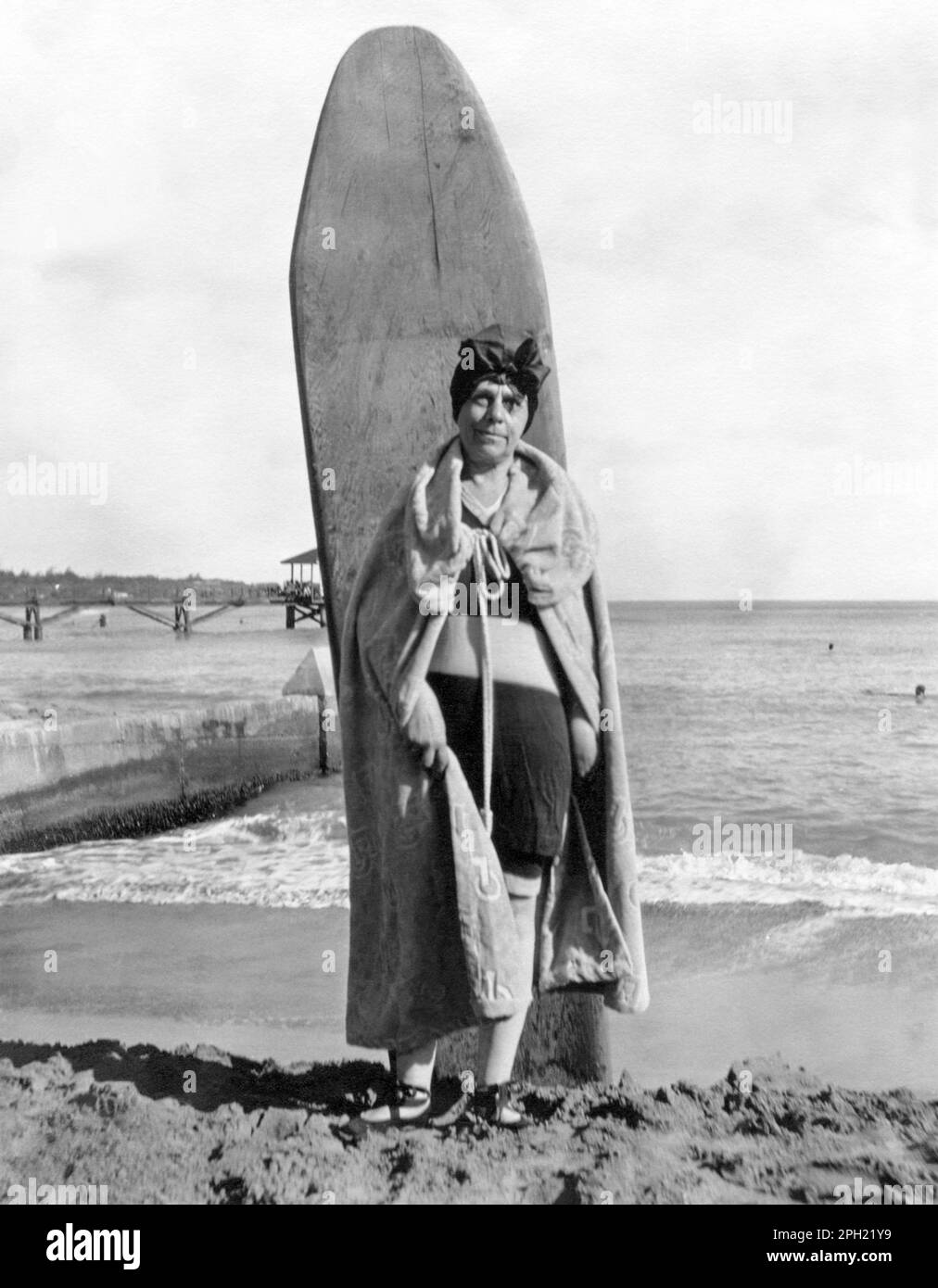 Ritratto vintage di una donna anziana che si posa con una tavola da surf in legno a Waikiki Beach a Honolulu, Hawaii, negli anni '1920s. Foto Stock