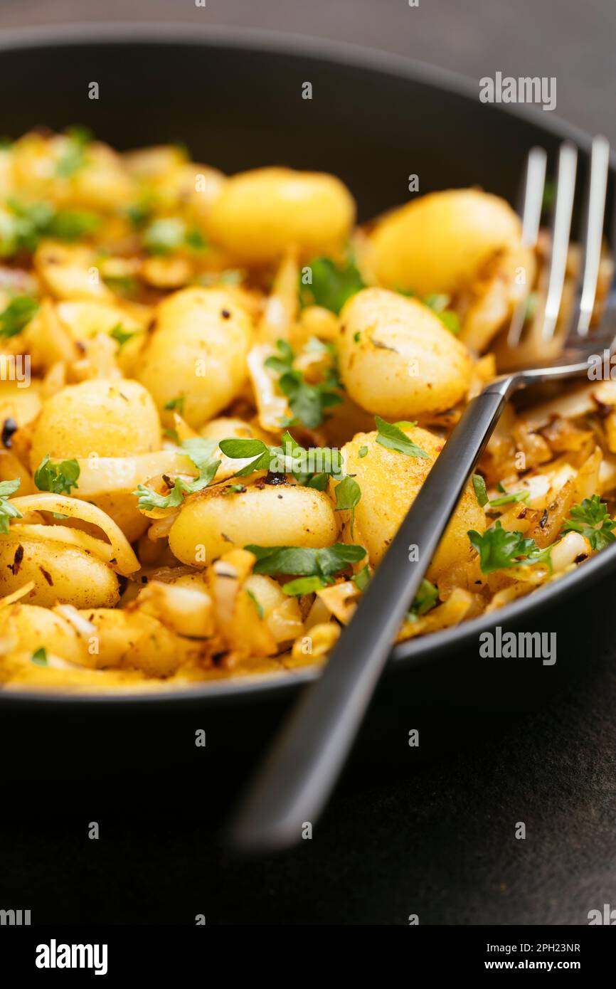 Gnocchi fritti con cavoli tritati e spezie cajun. Foto Stock