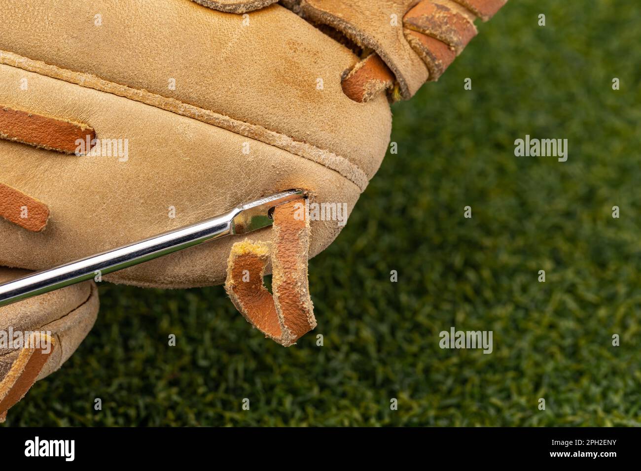 Riparazione dei lacci dei guanti da baseball con ago di allacciatura. Rifacimento dei guanti, riparazione e manutenzione di attrezzature sportive. Foto Stock