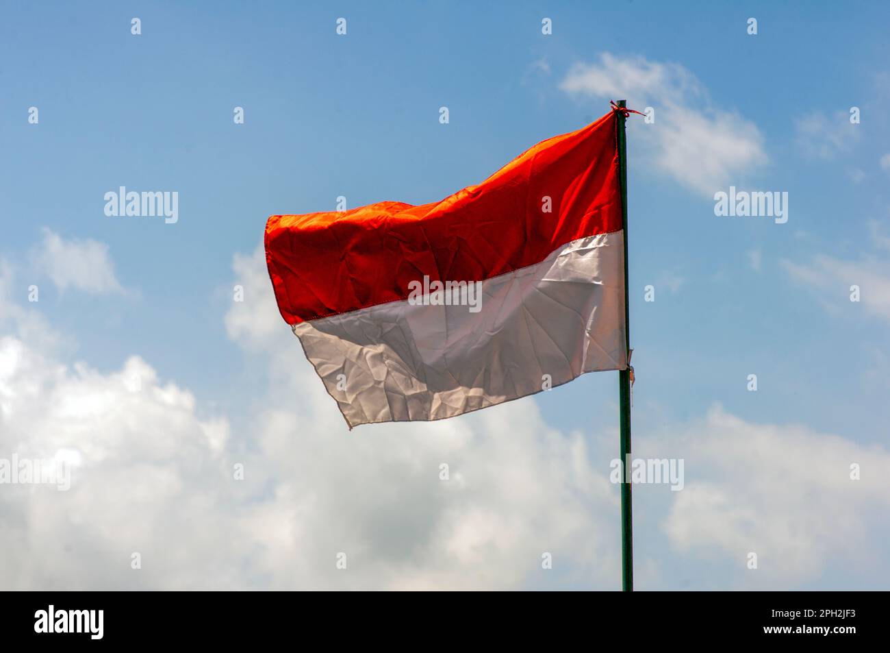 Una bandiera indonesiana su carta vecchia con sfondo cielo blu Foto Stock