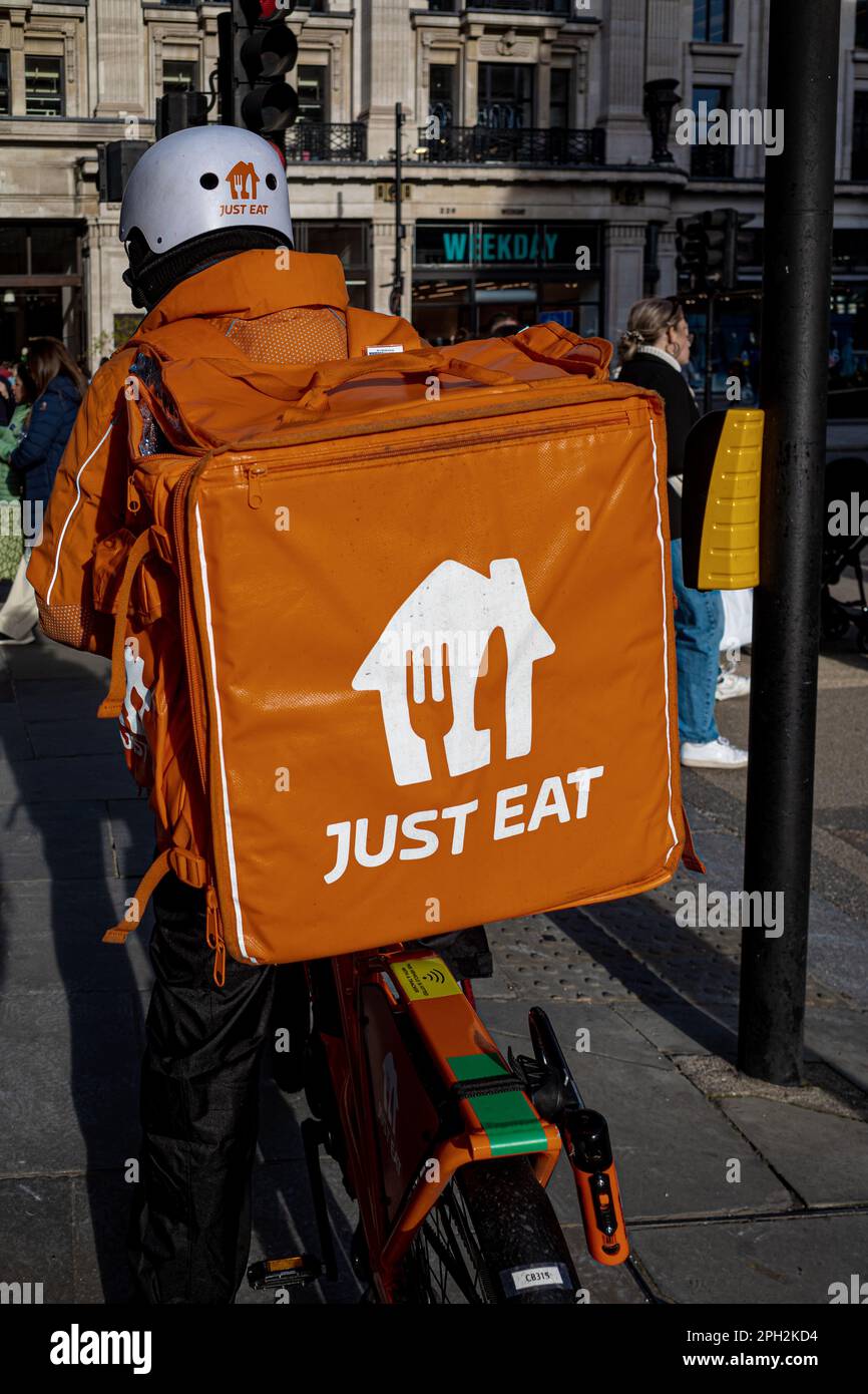 Basta mangiare fast food consegna corriere nel centro di Londra. Il corriere di consegna del cibo giusto orientale che porta il vestito arancione della società JustEat. Foto Stock