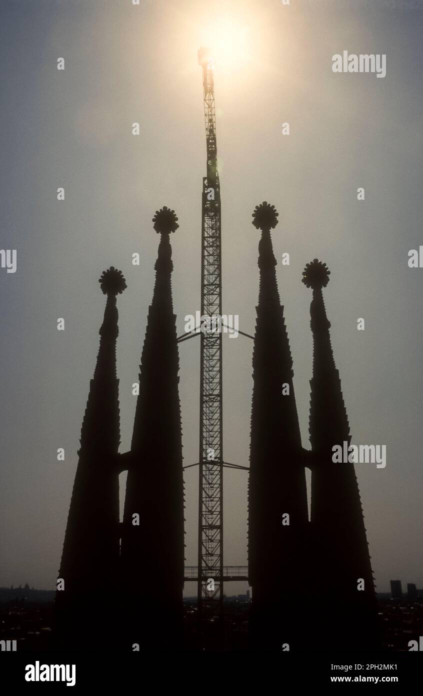1991 immagine dell'archivio della silhouette dei lavori di costruzione della Sagrada Familia a Barcellona. Mostra le torri della chiesa con una gru a torre che si stagliano contro il sole. Foto Stock