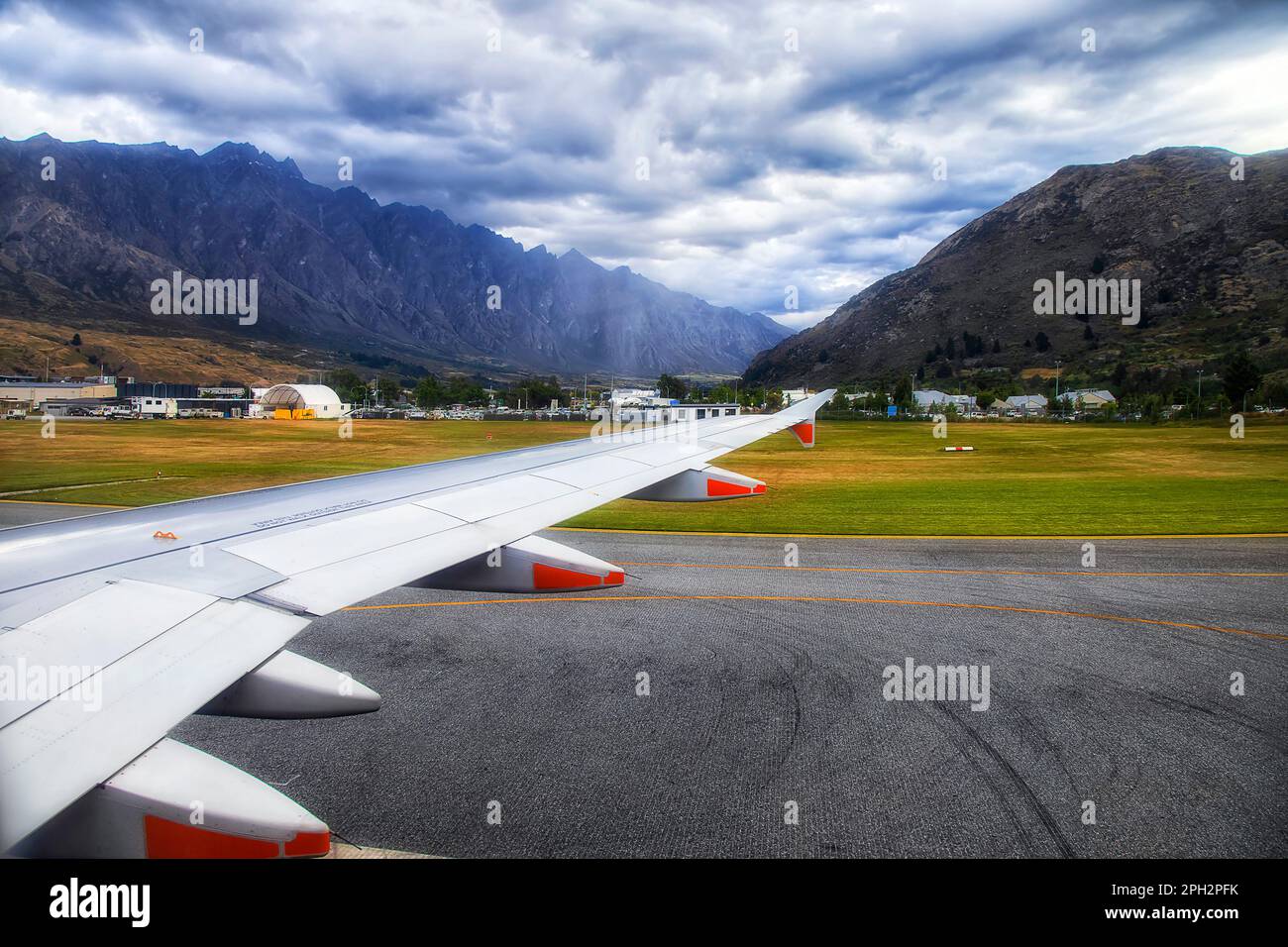 Aereo passeggeri sulla pista dell'aeroporto di Queenstown circondato da montagne panoramiche - popolare destinazione turistica in Nuova Zelanda. Foto Stock