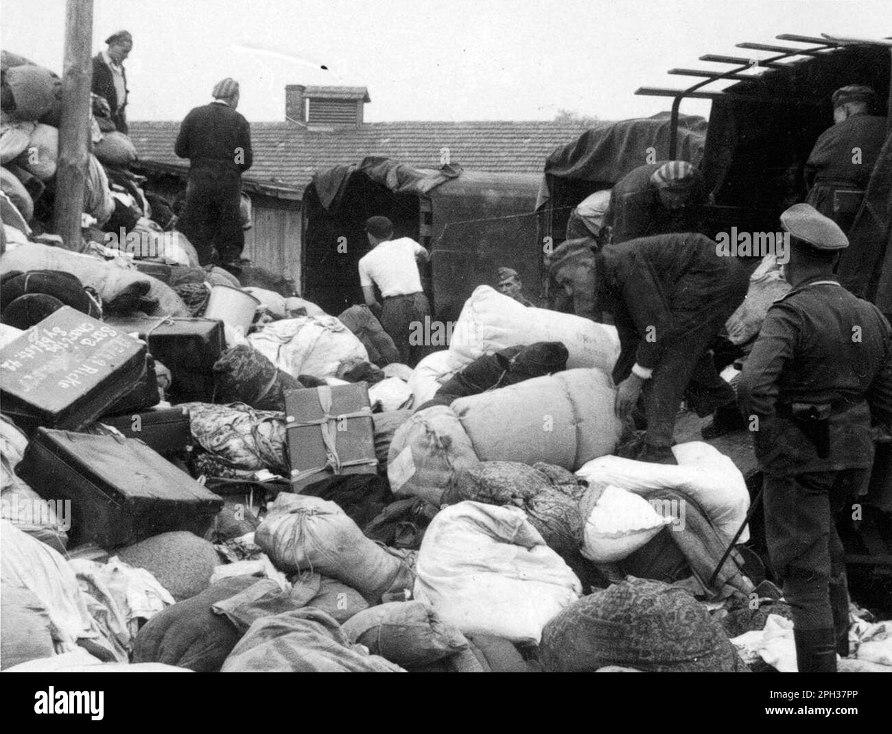 La caserma 'Kanada' nel campo di concentramento di Auschwitz, Polonia occupata dai tedeschi, durante l'Olocausto. I prigionieri ordinano i casi e le borse di coloro che sono stati inviati alla camera a gas all'arrivo. I magazzini sono stati chiamati 'Kanada' perché contenevano gli effetti saccheggiati dei prigionieri e sono stati considerati all'interno del campo come la terra di abbondanza. Foto Stock