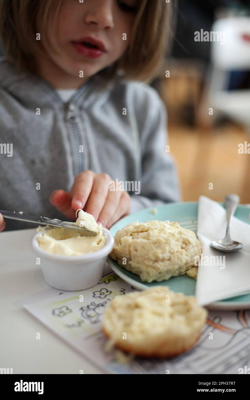 Bambino spalmare la crema su focaccine fresche Foto Stock